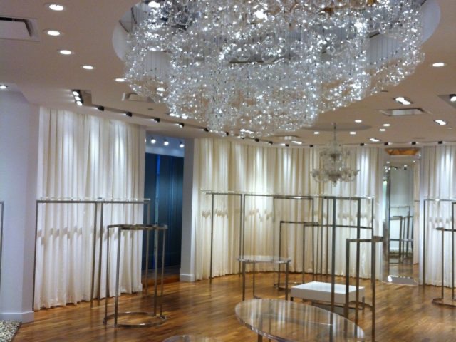 Boutique interior with chandelier, white drapery and hardwood floor