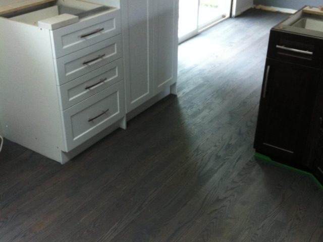 Kitchen cabinetry over dark hardwood flooring