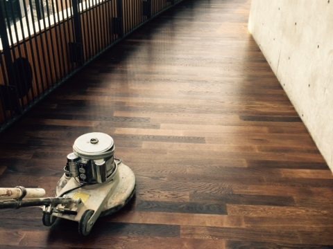Floor machine refinishing dark wood stairs mid-project